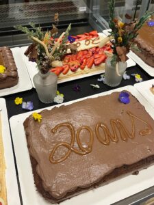 Gâteau au chocolat avec l’inscription 20 ans, entouré de fraisiers et fleurs comestibles, réalisé par Charlie & Tom